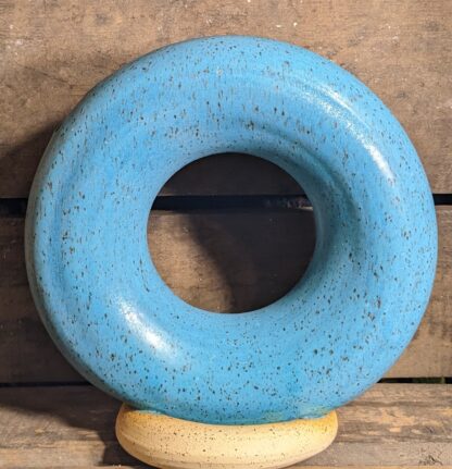 donut vase of PSH 455 speckle clay body, glazed in matte turquoise sitting atop an unglazed donut foot.